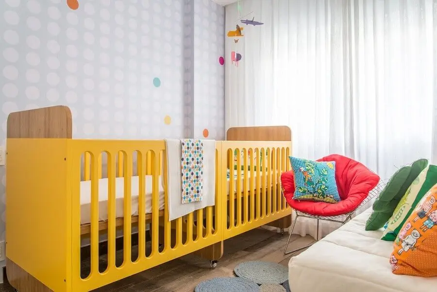 quarto de bebê gêmeos planejado decorado com berço amarelo e papel de parede neutro Foto Natoca Design