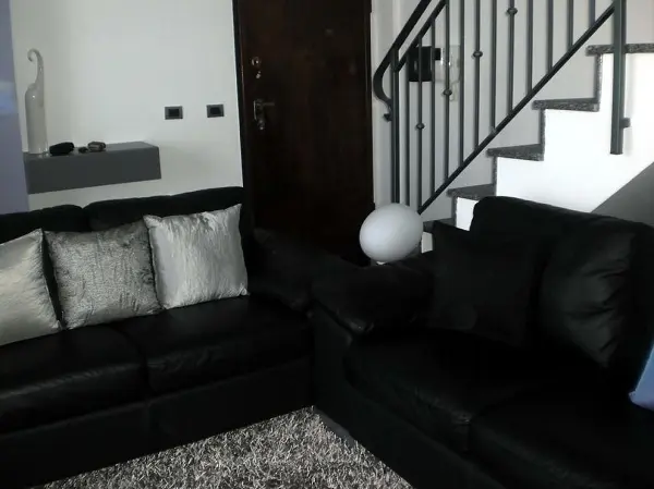 Dois conjuntos de sofá preto de 2 lugares complementam a decoração da sala