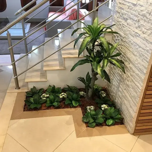 Mini jardim ao pé da escada feito com plantas artificiais