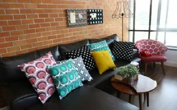 Que tal, sofá preto, almofadas coloridas e parede de tijolinhos?