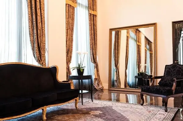 Decoração clássica com sofá preto e espelho