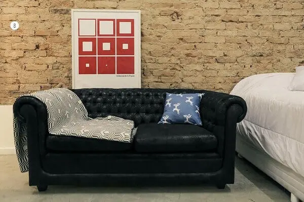 Sofá preto e parede de tijolinhos da sala de estar