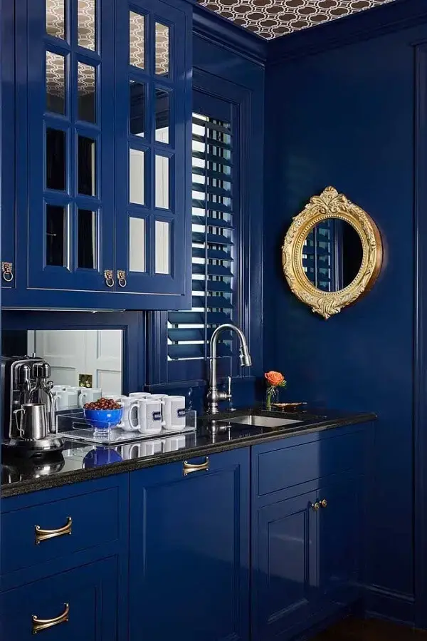 A moldura dourada do espelho redondo traz ainda mais elegância para a cozinha azul
