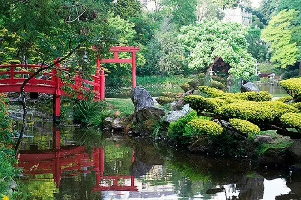 A ponte vermelha se destaca por entre a vegetação do Jardim Japonês