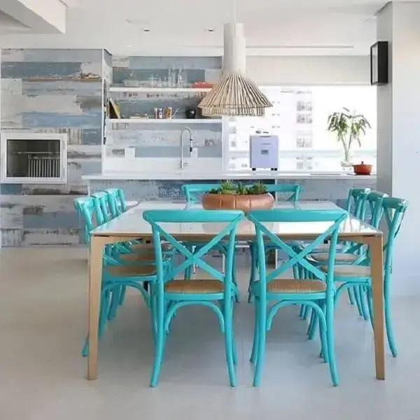 As cadeiras em tons de azul turquesa transmitem requinte para essa sala de jantar integrada com a churrasqueira. Projeto SP Estúdio
