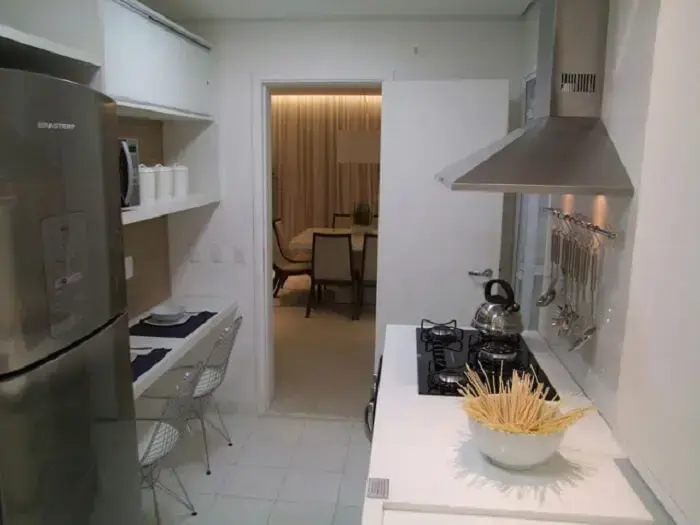 Cozinha compacta com bancadas brancas e aço inox