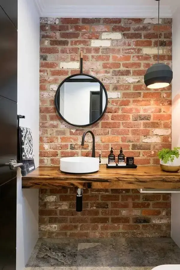 decoração rústica com espelho redondo para banheiro com bancada de madeira e parede de tijolinho Foto MdeMulher