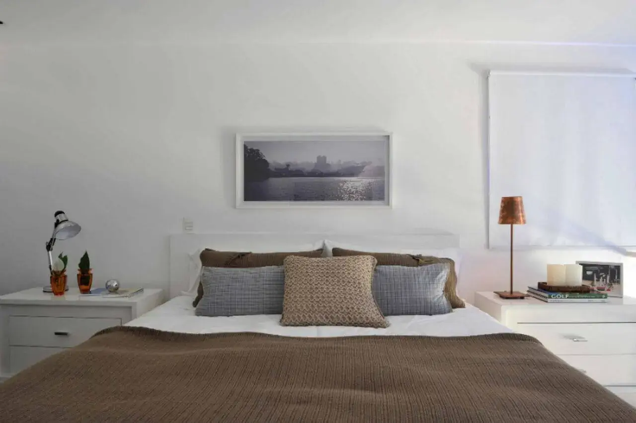 quarto de casal moderno - cama centralizada, em frente à quadro e paisagem com moldura branca