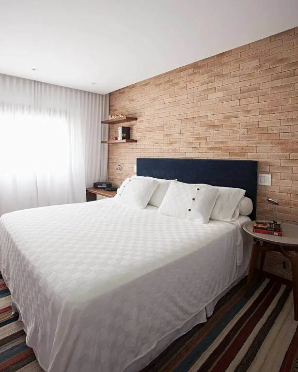quarto de casal moderno - cama com lençois brancos em frente a uma parede de tijolos
