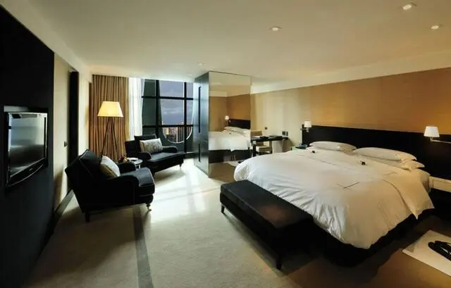 quarto de casal moderno - cama com lençóis brancos em frente a poltronas pretas