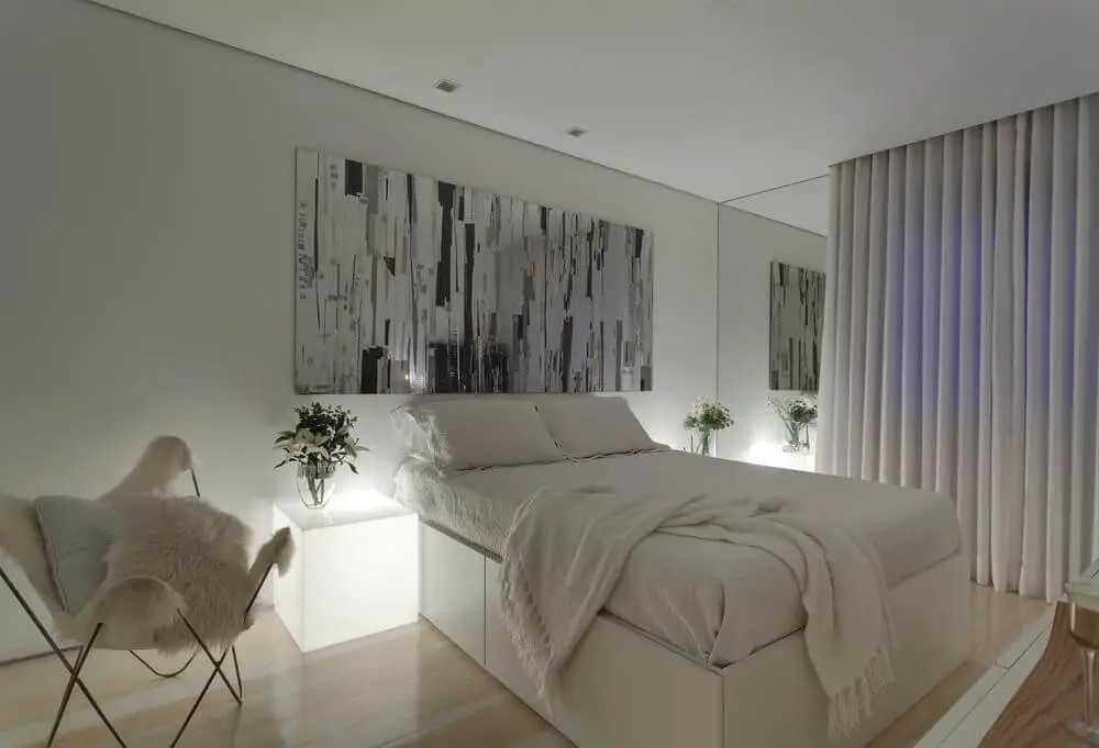 quarto de casal moderno - cama em frente à quadro abstrato e ao lado de mesa iluminada