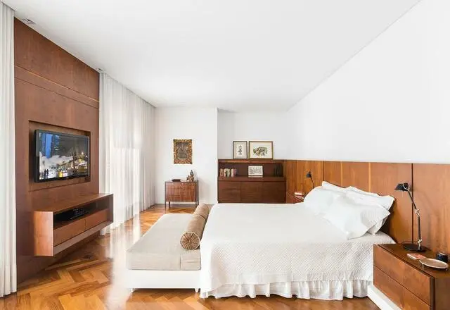 quarto de casal moderno - cama em frente a painel em madeira com televisão e nicho