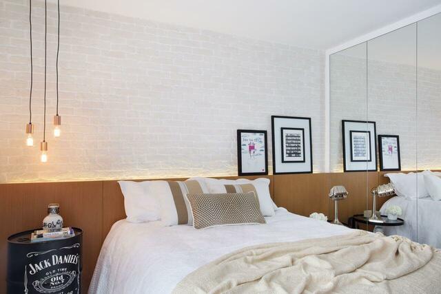 quarto de casal moderno - cama em frente a parede de tijolos brancos e quadros com moldura preta