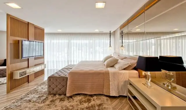 quarto de casal moderno - cama em parede de espelhos em frente a uma parede de madeira com televisão afixada