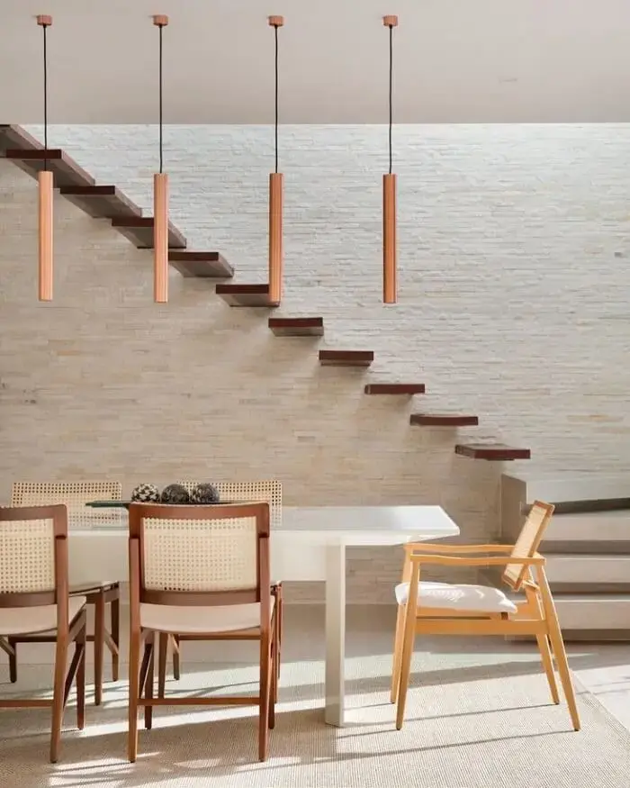 A escada flutuante de madeira complementa a decoração da sala de jantar