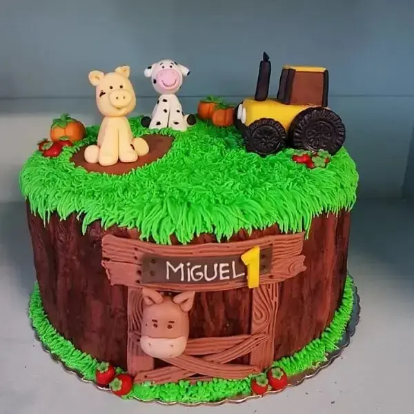 The little farm party is represented in the cake with grass, tractor, wooden fence and animals