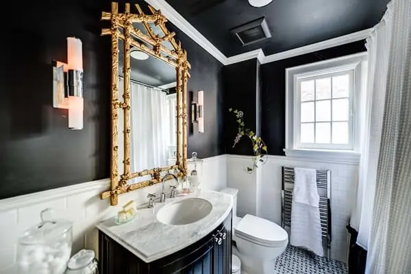 A moldura na cor dourado do espelho encanta a decoração do banheiro