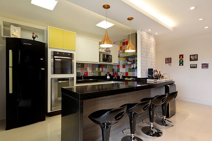 Cozinha americana com azulejos coloridos e geladeira preta