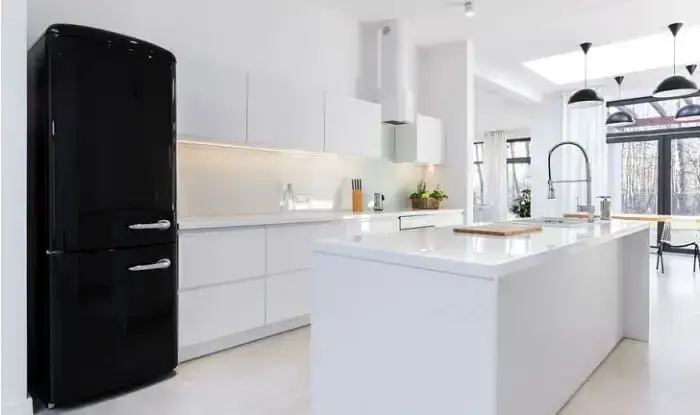 Cozinha clássica conta com armários em branco e geladeira preta retrô