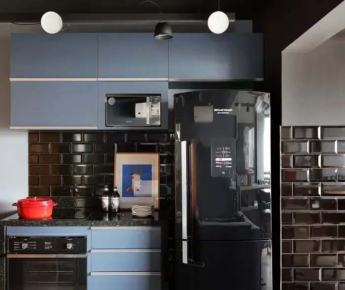 Cozinha com decoração formada por armários azul e geladeira preta