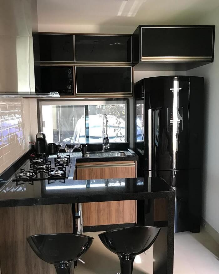 Cozinha compacta com cooktop e geladeira preta embutida