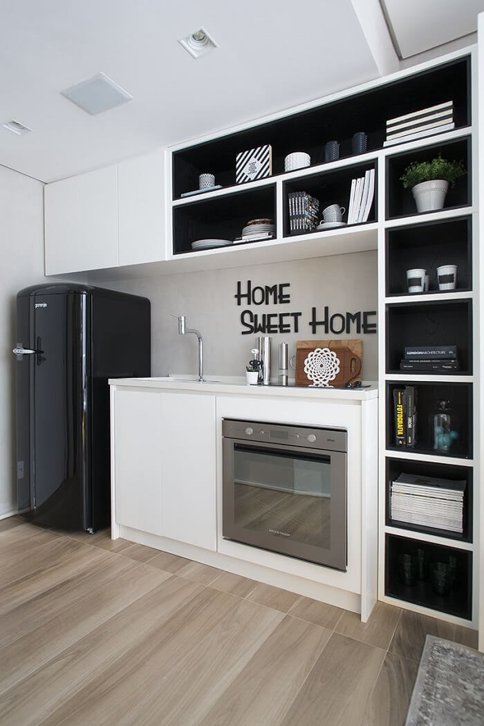 Cozinha compacta com diversos nichos e geladeira preta