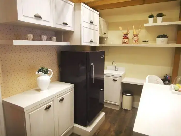 Cozinha compacta conta coma presença de uma geladeira preta