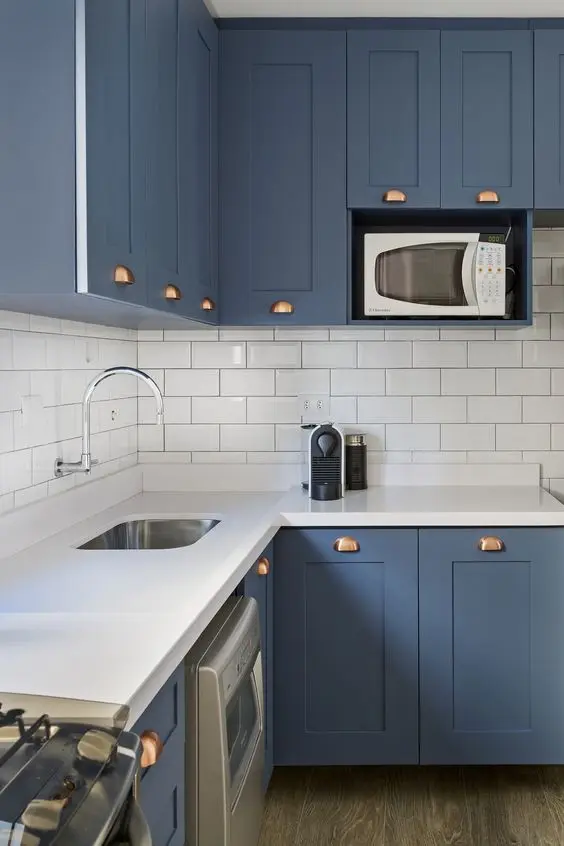 Cozinha moderna com silestone branco e armário de canto de parede azuis