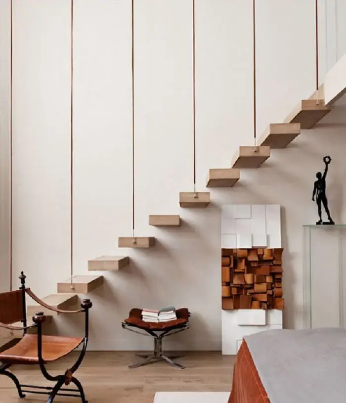 Escada flutuante apoiada por cordões complementa a decoração com estilo minimalista