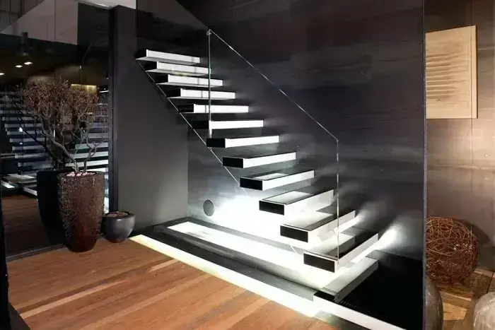 Escada flutuante de concreto com lateral de vidro e iluminação sofisticada
