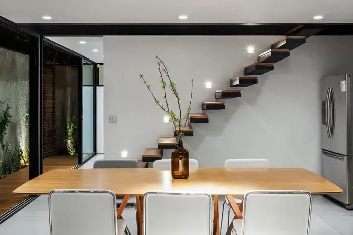 Escada flutuante de madeira com pontos de iluminação na parede. Fonte All Architecture Designs