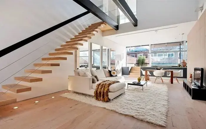 Escada flutuante de madeira encanta e complementa a decoração desta sala de estar