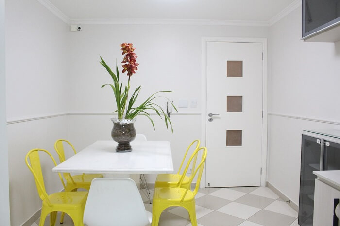 Mesa retangular branca e cadeiras amarelas para o ambiente de cozinha