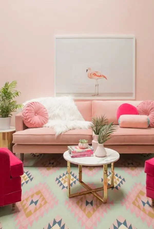 Sala de estar com sofá retrô na cor rosa e mesa de centro com pés em dourado
