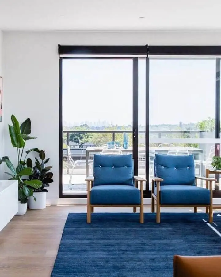 Sala de estar decorada com poltronas e tapete azul Foto Histórias de Casa