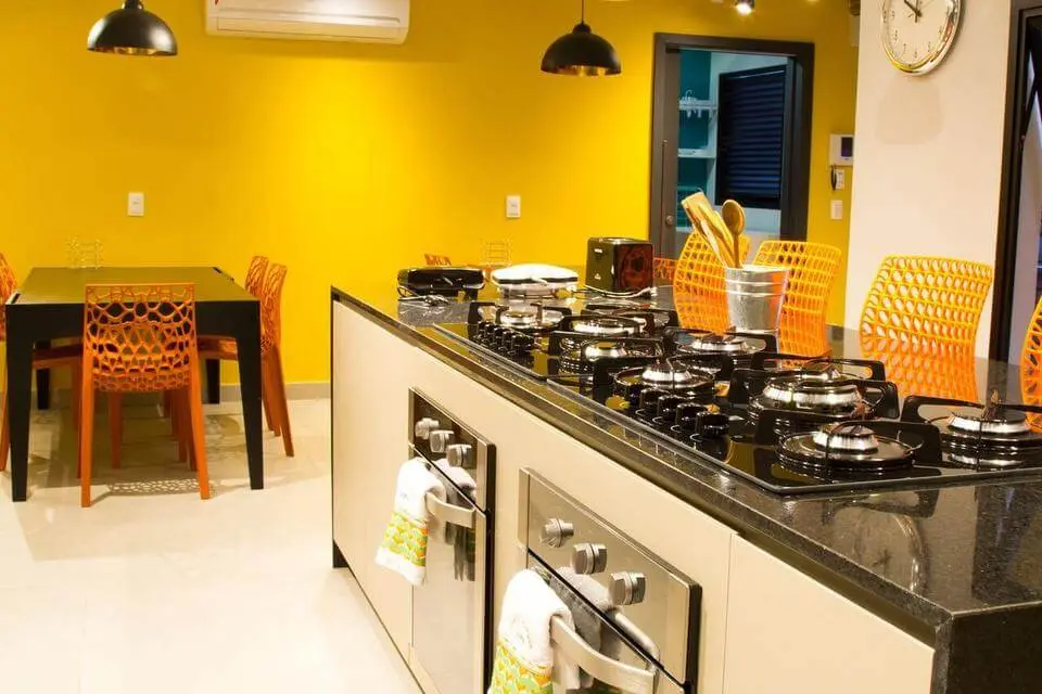 fogão cooktop - cozinha com parede amarela e cadeiras laranjas 