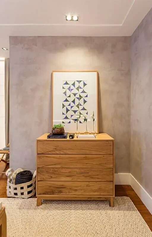 quarto decorado com cômoda de madeira e parede de cimento queimado