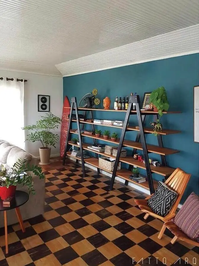 sala decorada com estante simples e parede azul petróleo Foto FATTO