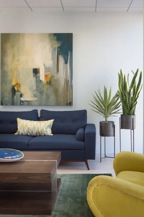 sofá azul escuro para sala decorada com quadro grande e vasos de chão  Foto Jeito de Casa