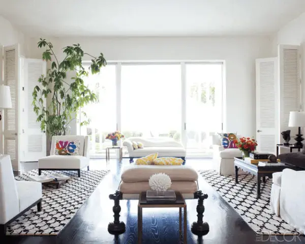 A luz natural invade esta sala de estar com tapete preto e branco geométrico