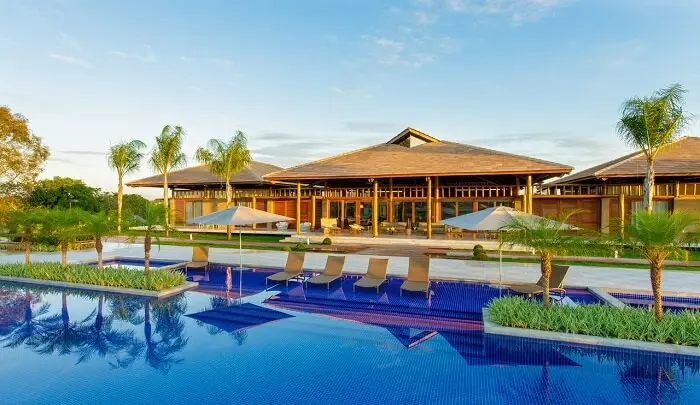 Casa de madeira com varanda conta com a presença de piscina e paisagismo encantador