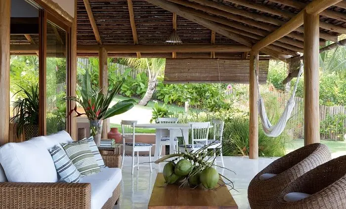 Casa de praia com varanda de madeira, móveis rústicos e rede para descanso