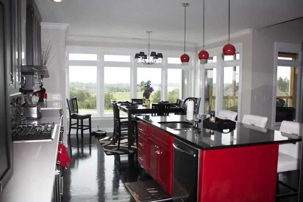 Cozinha com bancada de granito preto e armários em tons de vermelho