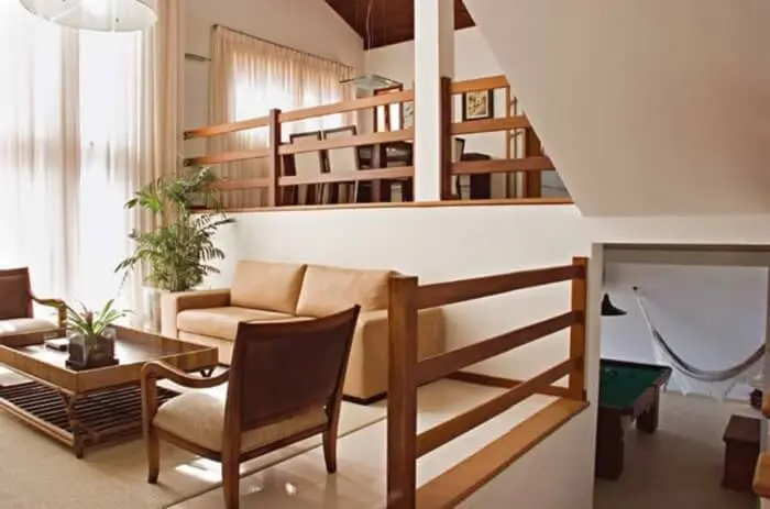 Guarda corpo de madeira utilizado dentro dessa residência se harmoniza com a decoração