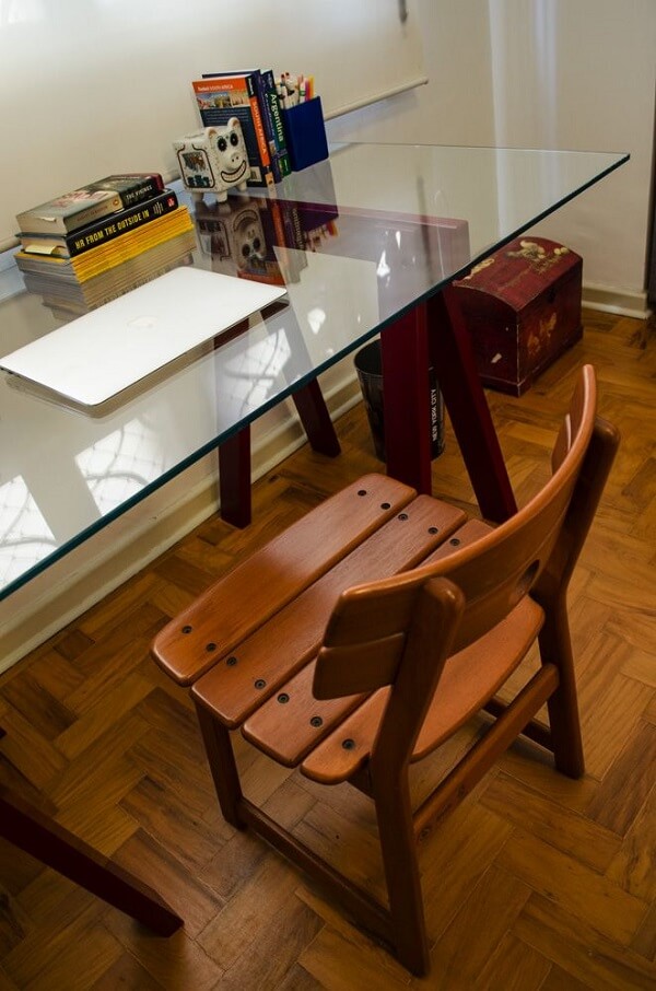 Home office com mesa de vidro e cadeira de madeira