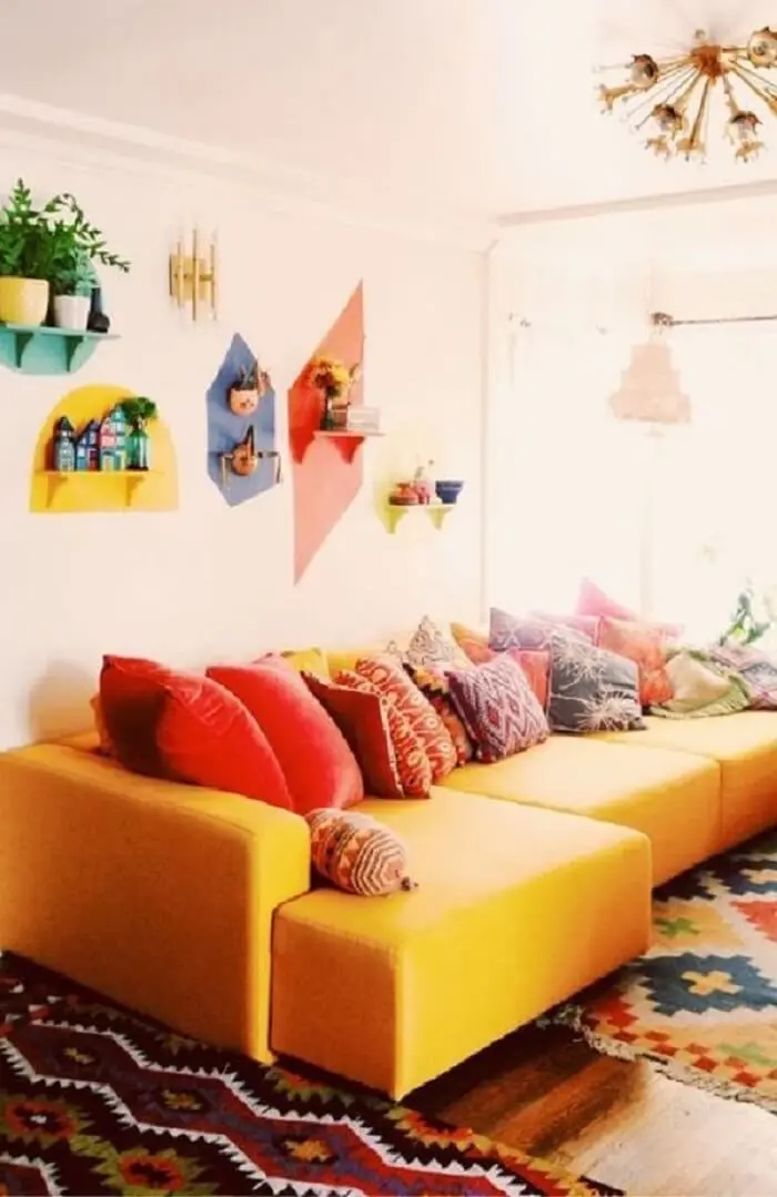 O tecido para sofá na cor amarela se conecta com as almofadas coloridas