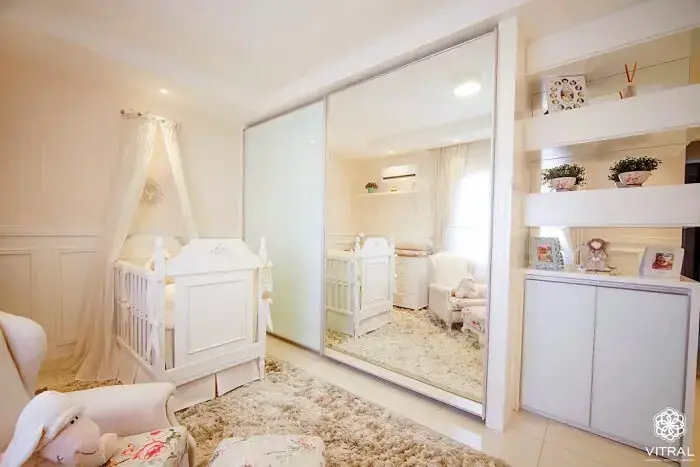Quarto de bebê com berço provençal e espelho no armário amplia o espaço do ambiente