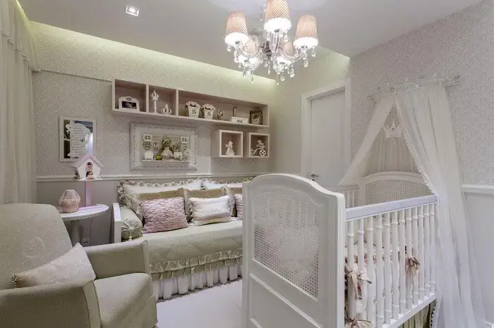Quarto de bebê com berço provençal, lustre e papel de parede claro