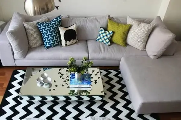 Sala de estar com sofá cinza e tapete chevron preto e branco