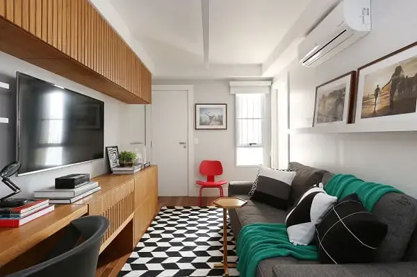 Sala de estar pequena com sofá cinza e tapete preto e branco